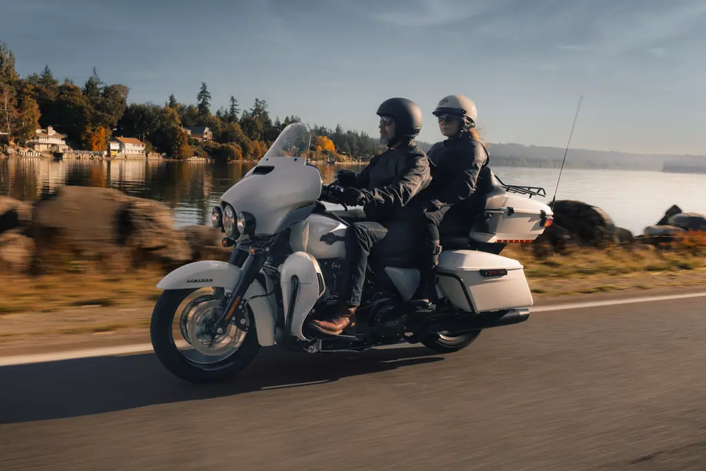 Harley-Davidson Ultra Limited von 2024, weiß, zu zweit auf einer Uferstraße am See gefahren, Tour-Pak und untere Verkleidungen im Blick