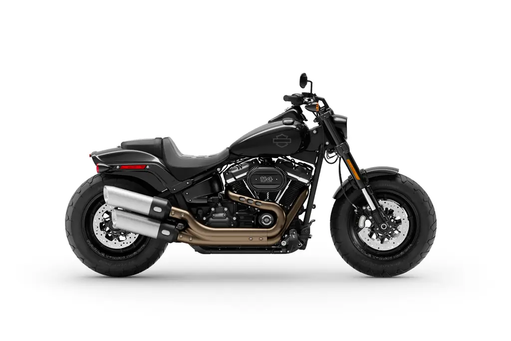 Seitenansicht einer schwarzen Harley-Davidson Fat Bob 114 von 2020 mit übereinanderliegenden Doppelauspuffrohren und breitem Vorderreifen