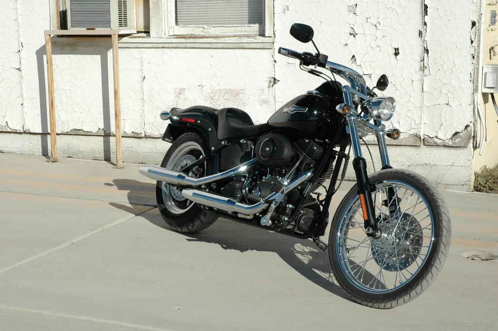 Eine schwarze Harley-Davidson Night Train mit Solositz, schmalem Speichen-Vorderrad und verchromtem Auspuff, vor einem Gebäude geparkt.