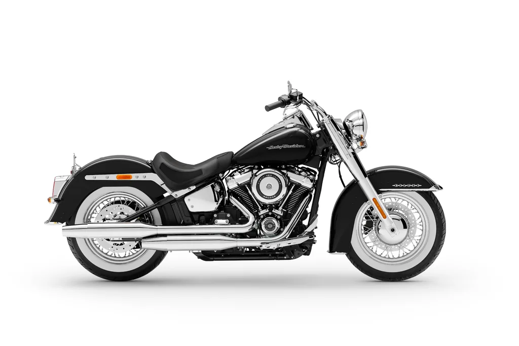 Studioansicht von rechts einer schwarzen Harley-Davidson Softail Deluxe von 2020 mit Weißwandreifen, verchromtem Auspuff und Fahrer-Trittbrettern.
