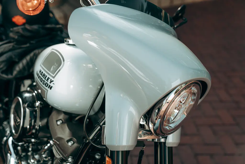 Nahaufnahme der Mini-Verkleidung, des kurzen schwarzen Windschilds und des runden Scheinwerfers einer Harley-Davidson Sport Glide FLSB von 2023.