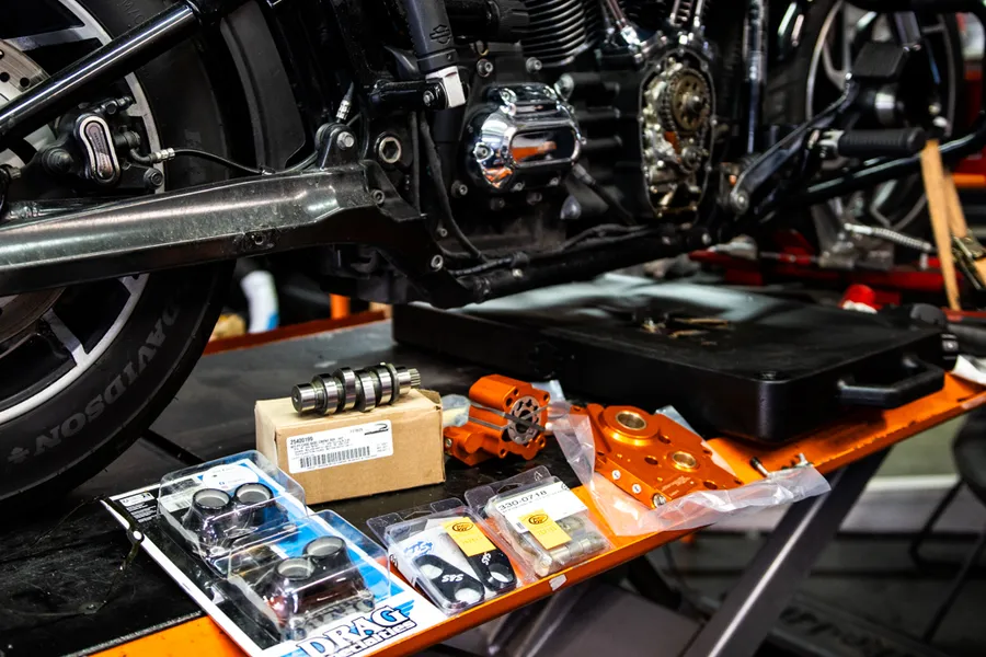 Drag Specialties Teile auf einer Werkstattbank neben einem Harley-Davidson Motor auf der Hebebühne